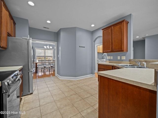 kitchen with stainless steel range with electric stovetop, sink, light tile patterned floors, and a notable chandelier