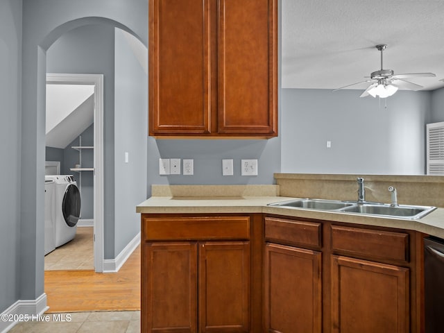 kitchen with sink, light tile patterned floors, ceiling fan, washing machine and dryer, and stainless steel dishwasher