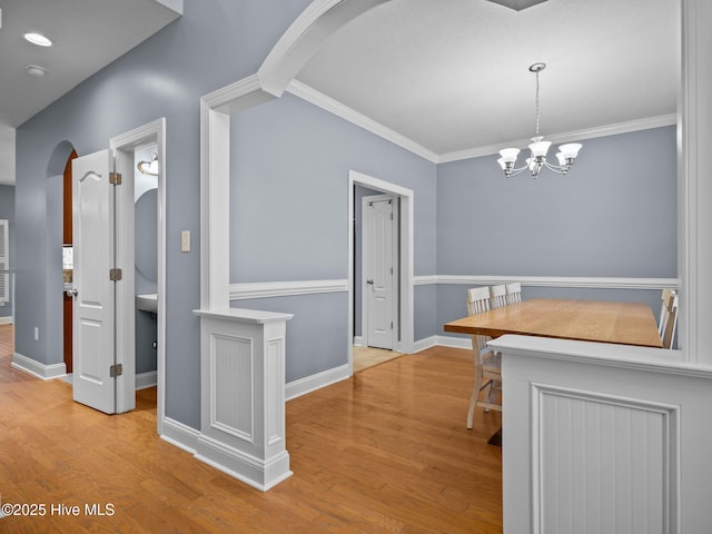 dining area featuring crown molding, a notable chandelier, and light hardwood / wood-style floors