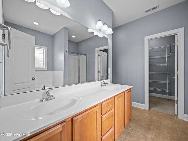 bathroom featuring vanity, a shower with shower door, and tile patterned flooring