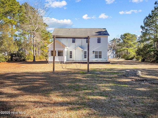 back of property with a lawn and an outdoor fire pit