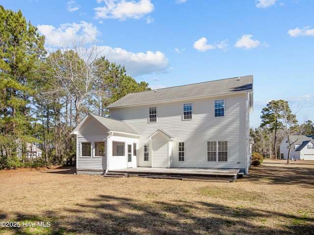 rear view of house featuring a wooden deck and a lawn