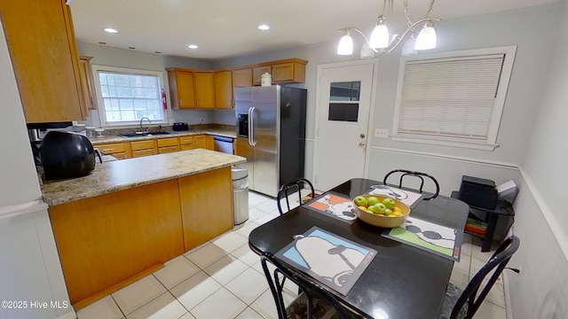 kitchen featuring light tile patterned flooring, sink, hanging light fixtures, kitchen peninsula, and stainless steel appliances