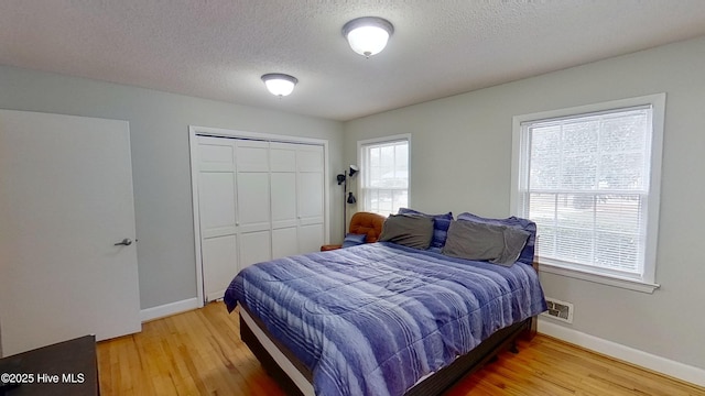 bedroom featuring hardwood / wood-style floors, a textured ceiling, and a closet