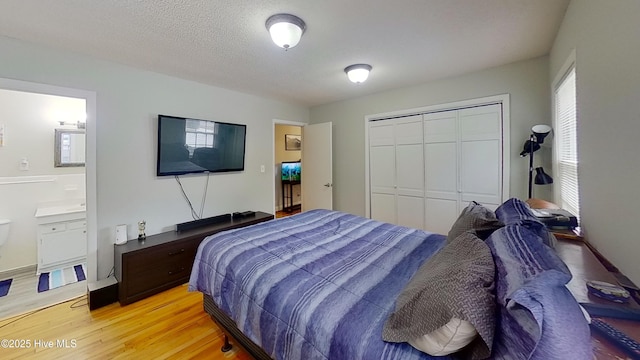 bedroom featuring ensuite bathroom, a closet, a textured ceiling, and light wood-type flooring