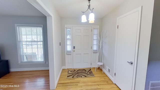 foyer entrance with a chandelier and light wood-type flooring