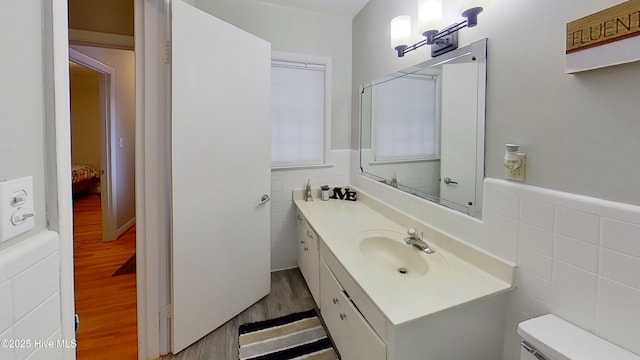 bathroom with hardwood / wood-style flooring, vanity, tile walls, and toilet