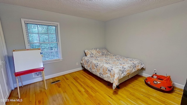 bedroom featuring hardwood / wood-style floors and a textured ceiling