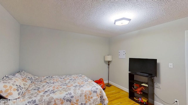 bedroom with a textured ceiling and light wood-type flooring