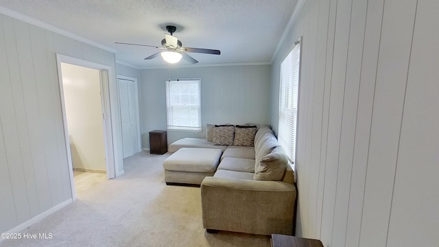 living room featuring ceiling fan, light colored carpet, ornamental molding, and a textured ceiling