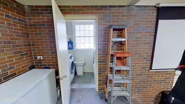 bathroom with separate washer and dryer, concrete floors, and brick wall