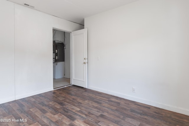 spare room with baseboards, dark wood-style flooring, and visible vents