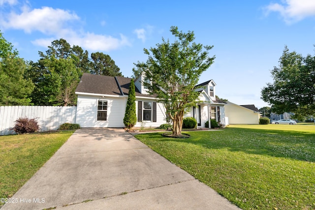 view of front facade with a front lawn, driveway, and fence