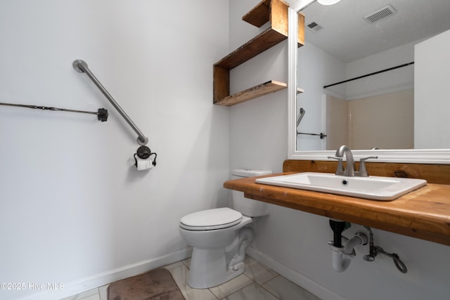 bathroom featuring toilet, visible vents, baseboards, and a sink