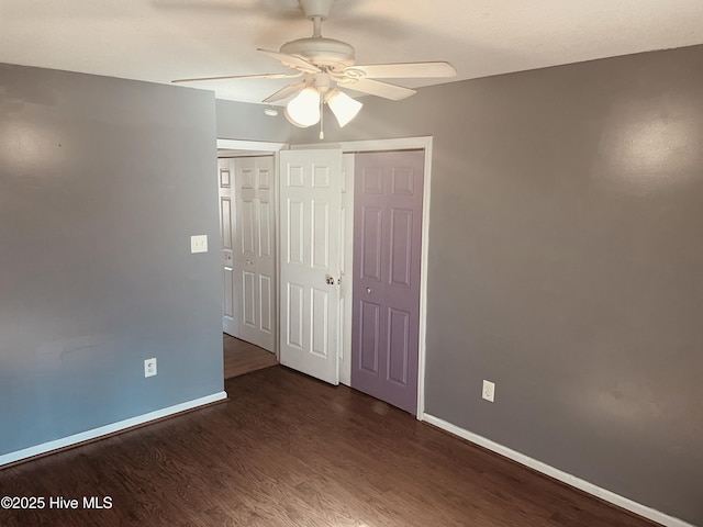 spare room featuring ceiling fan, dark wood finished floors, and baseboards