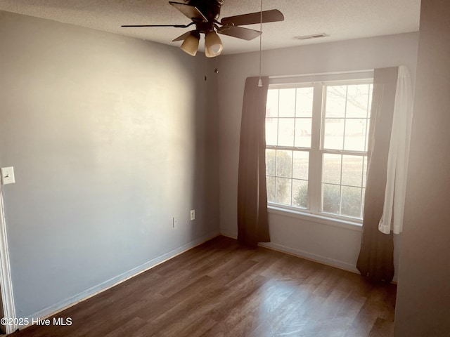 unfurnished room with a healthy amount of sunlight, a textured ceiling, visible vents, and wood finished floors