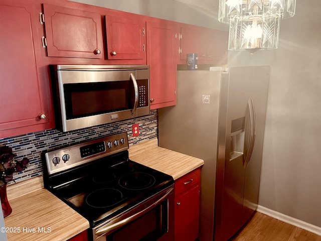 kitchen featuring baseboards, light wood-style flooring, stainless steel appliances, light countertops, and backsplash