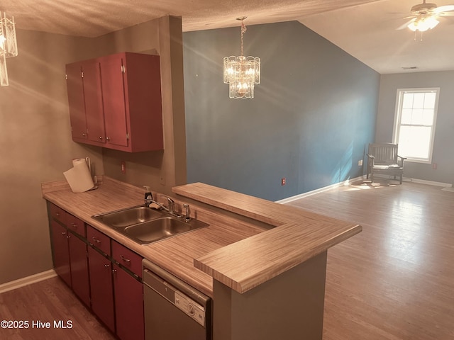 kitchen with dishwasher, dark wood-style floors, light countertops, pendant lighting, and a sink