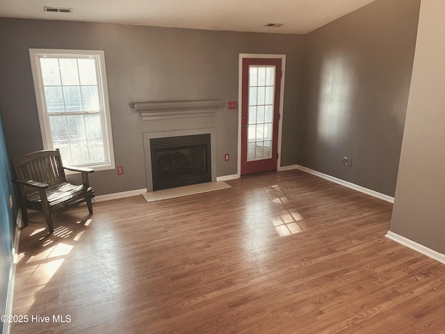 unfurnished living room featuring a healthy amount of sunlight, baseboards, and wood finished floors