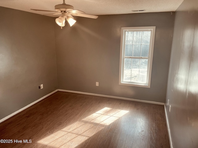 spare room featuring baseboards, a textured ceiling, visible vents, and wood finished floors