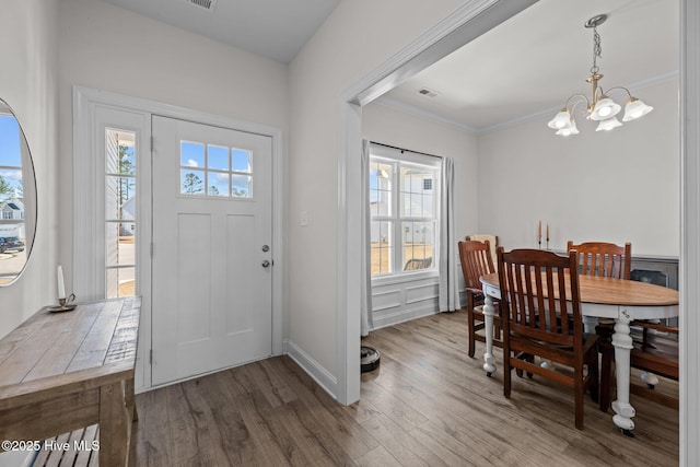 entrance foyer with an inviting chandelier, ornamental molding, and wood-type flooring