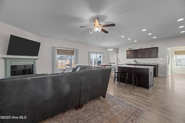 living room featuring a healthy amount of sunlight, sink, ceiling fan, and light hardwood / wood-style flooring