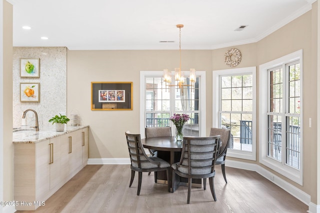 dining space featuring light wood finished floors, baseboards, an inviting chandelier, and ornamental molding