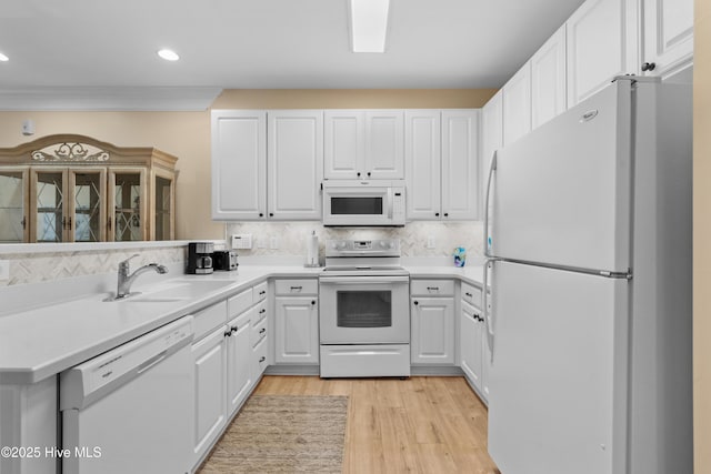 kitchen with sink, white cabinets, white appliances, light hardwood / wood-style floors, and backsplash