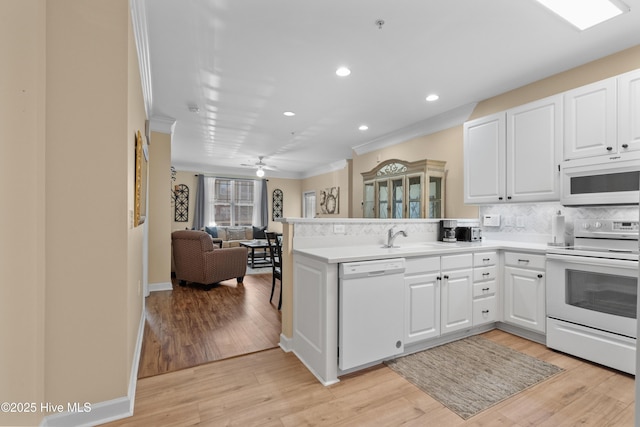 kitchen featuring tasteful backsplash, white appliances, light hardwood / wood-style floors, and white cabinets