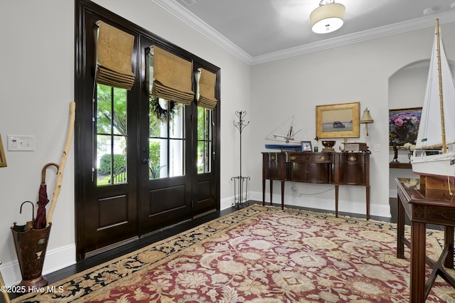 entrance foyer with crown molding, arched walkways, baseboards, and wood finished floors