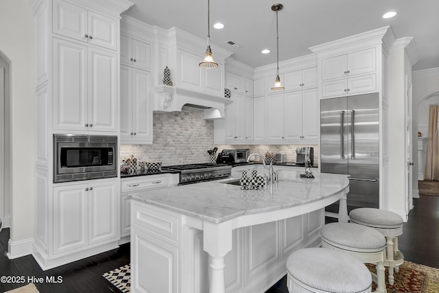 kitchen featuring white cabinets, dark wood-type flooring, built in appliances, and tasteful backsplash
