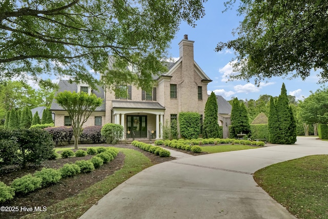 traditional-style house with brick siding, french doors, and a chimney
