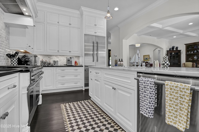 kitchen with white cabinetry, high end appliances, wall chimney exhaust hood, arched walkways, and beamed ceiling