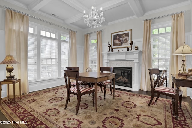 dining room featuring coffered ceiling, a healthy amount of sunlight, a decorative wall, and a fireplace with flush hearth