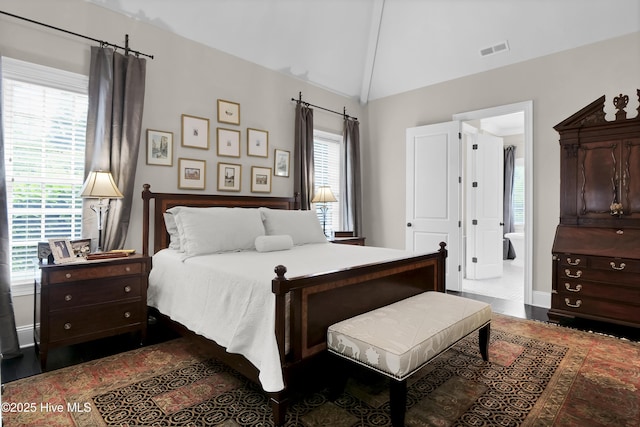 bedroom featuring connected bathroom, visible vents, and lofted ceiling