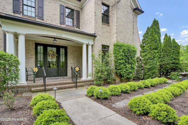 doorway to property featuring a porch and brick siding