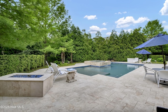 view of swimming pool with a patio area, a fire pit, and a pool with connected hot tub