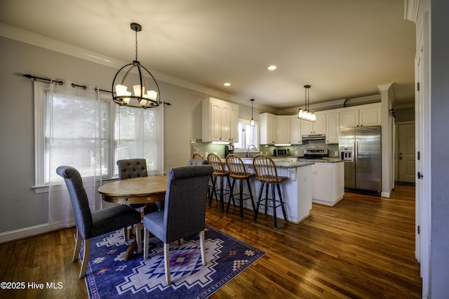 dining space with crown molding, sink, a chandelier, and dark wood-type flooring