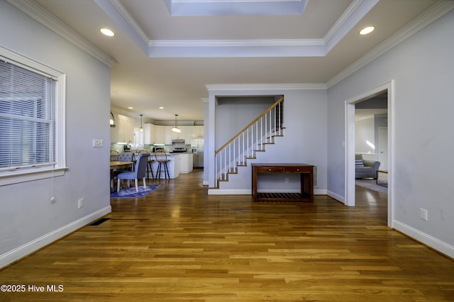 foyer with crown molding, a tray ceiling, and hardwood / wood-style floors