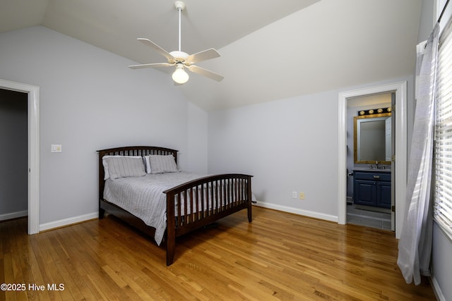 bedroom with vaulted ceiling, ensuite bathroom, sink, ceiling fan, and light wood-type flooring