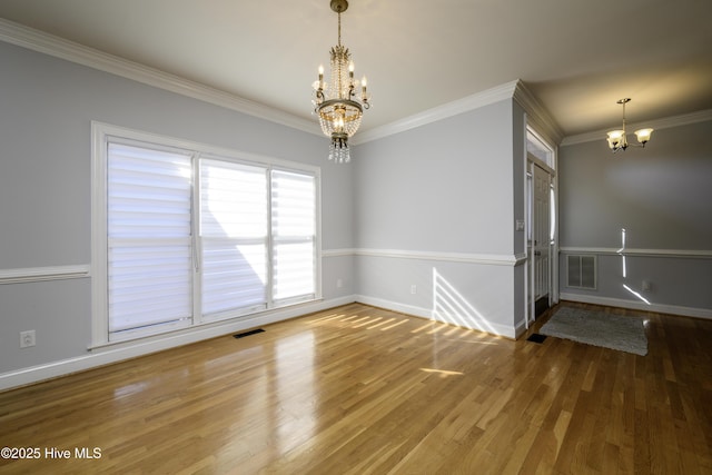 unfurnished room with ornamental molding, wood-type flooring, and a notable chandelier