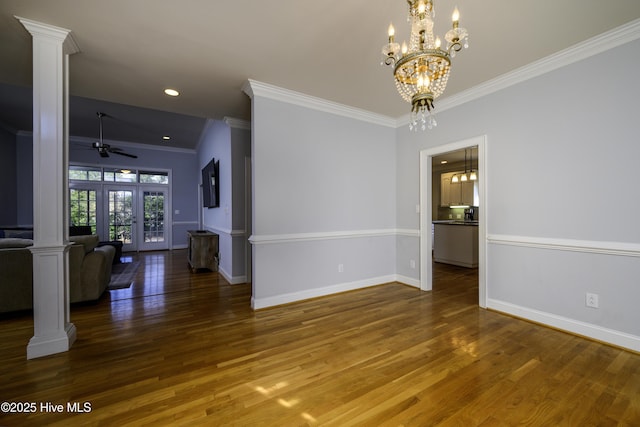 spare room featuring ornamental molding, ceiling fan with notable chandelier, wood-type flooring, and decorative columns