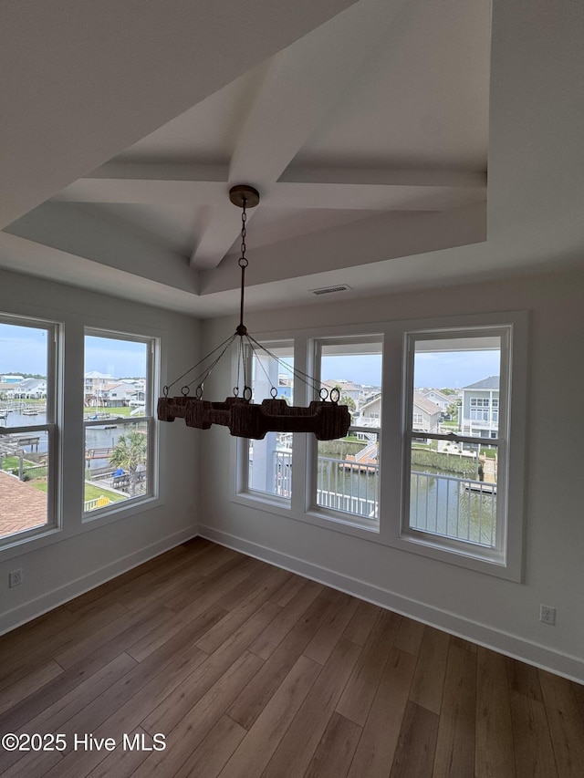 36 Fairmont St, Ocean Isle Beach, NC 28469 - unfurnished dining area with a raised ceiling, a chandelier, dark wood-type flooring, and baseboards