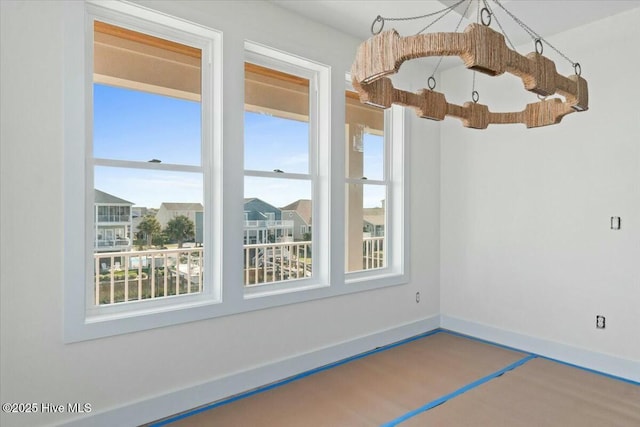 unfurnished room featuring an inviting chandelier and baseboards