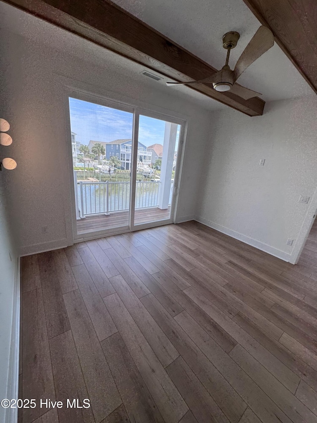 36 Fairmont St, Ocean Isle Beach, NC 28469 - unfurnished living room featuring ceiling fan, hardwood / wood-style floors, baseboards, beamed ceiling, and a water view