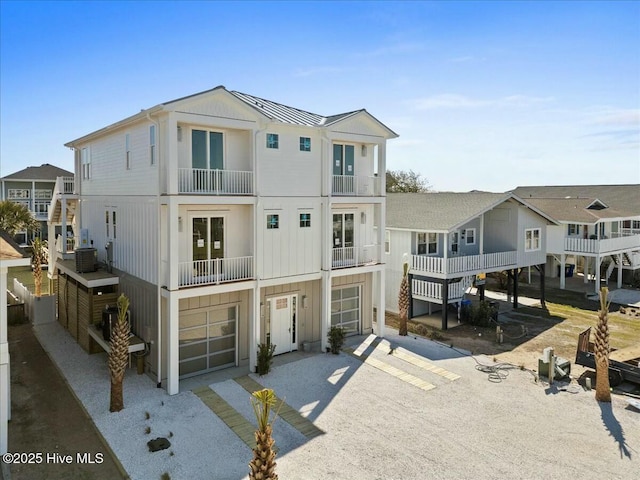 view of front of home with a residential view, central AC, driveway, an attached garage, and a standing seam roof