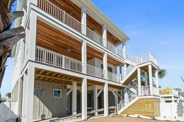 back of house with stairway, board and batten siding, and a ceiling fan