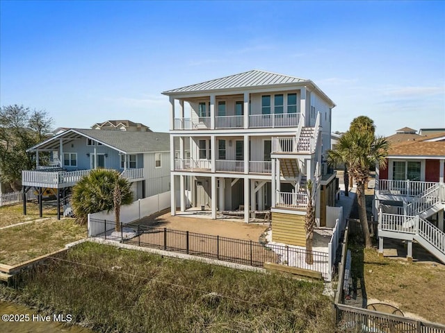 back of house with metal roof, a fenced backyard, a balcony, a patio area, and a standing seam roof