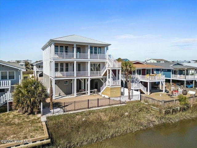 rear view of house with a patio, stairway, a fenced backyard, a water view, and metal roof