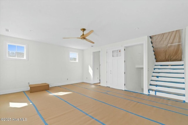 interior space with baseboards, stairs, and ceiling fan